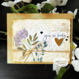 Neutral mixed-media card using the script-and-envelope background with pressed florals and a 'you are lovely' sentiment.