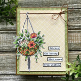 The planter with orange blooms on a plaid card with a twine bow, with "Embrace the beauty that comes from within."
