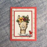 The llama in a floral crown on a coral-matted card over denim — 'Llama tell ya something.'