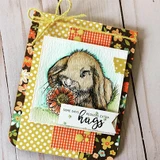 Yellow and orange floral card with the bunny in tans nosing an orange daisy, tied with yellow raffia, above a banner reading Some days require extra hugs.