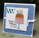 Grinning cake with candles, 'Happy Birthday to you,' on a blue word-print card.