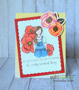 Card with a red scalloped frame on mint, the girl in denim overalls among coral blooms, and the grow-and-change sentiments in script.