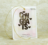 Oversized bold block-letter greeting words stamped in red rubber and colored on a handmade card reading "Congrats."