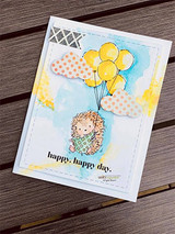 Card with yellow watercolor sky and patterned clouds; the hedgehog rises on yellow and orange balloons above “happy, happy day.”
