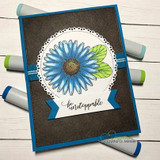 Card with a hand-colored blue daisy on a brown mat, stamped 'be unstoppable.'