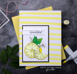 Yellow striped card with a small white panel showing a lemon slice and blossoms, styled with yellow patterned paper and a paperclip.