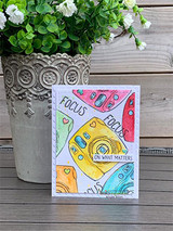 Small card with the instant camera colored in rainbow washes, stamped 'Focus on what matters.'