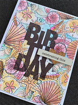 Seashell border of scallops, starfish and sand dollars framing a 'Birthday' die-cut in soft pastels.