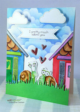 Whimsical card with snails on a hill under a sky of clouds and colorful houses.