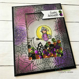 Witch girl in a spiderweb shaker card, 'happy Halloween,' in purples and greens.