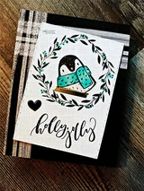 Card with a penguin in a leafy wreath and 'holly jolly'.