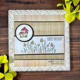 Birthday card with the plaid as a soft background behind mushrooms and wildflowers, 'Happy Birthday.'