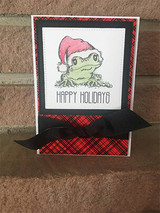 Santa-hat frog on a red plaid card with 'Happy Holidays.'