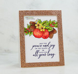 Card with the apple and pinecone bunch colored in red, green and gold, framed in rose gold glitter, above the script sentiment "May the peace and joy of the season be with you all year long."