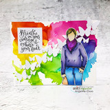 Rainbow watercolour card with white butterfly die cuts, the girl in a purple sweater, and 'Breathe in your courage & exhale your fear' stamped on the bright wash.
