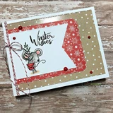 Card of a mouse holding a little tree with a winter-wishes sentiment over red-and-kraft paper.