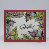 White panel with the feather border colored in olive, plum and gold, mounted on a brick red frame, with live thankfully lettered in the open center.