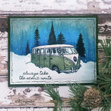 Handmade card featuring the vintage camper van among snowy pine trees, in a moody blue winter forest, stamped with 'Always take the scenic route'.