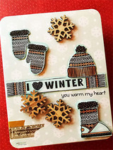 Cream card on red with colored mittens, a bobble hat and knit boot, wooden snowflakes and banners reading I love WINTER and you warm my heart.