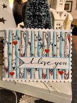 Scalloped card with birch trunks in pale blue and cream, small red hearts, and 'i love you' on a white strip.