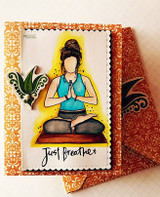 Card of the meditating girl in teal over orange ornate papers, 'just breathe.'