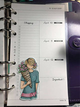 Colored planner girl with her flower bouquet clipped onto a ringed weekly planner page.