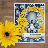 Card with the koala on a navy daisy background over a yellow doily, 'in this together.'