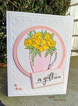 White embossed card with a blush circle and a cream mug of golden yellow flowers, a small panel across the bottom reading A gift for you.