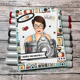 Bright card with a stamped girl in glasses holding the vintage camera over camera-print paper, with 'make memories' on a black banner.