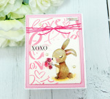 Pink card with the bunny colored brown holding flowers over a 'love' background, 'XOXO'