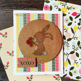 Card with the bunny colored on a circle over floral paper, 'XOXO'