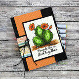 Cactus card layered on orange and patterned papers with twine, 'Friends like us stick together.'
