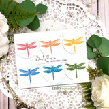 White card with six dragonflies colored in red, orange, yellow, blue, purple and green inside circles, and "Beauty lies in the simple little things" stamped beside them.