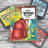 Bright card with a red backpack on a rainbow mixed media panel, Distress Oxide ink pads beside it, sentiment "Best Wishes FOR A GREAT YEAR."