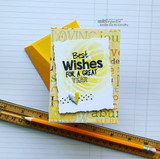 Card with "Best Wishes FOR A GREAT YEAR" stamped on a torn white panel over a yellow sunburst background, with a yellow envelope and a pencil.