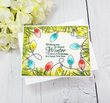 Handmade card featuring the string of vintage Christmas lights framing an A2 card, in soft greens with pine, stamped with 'May the light and joy of the season be yours'.