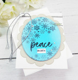 Snowflake heart on a blue medallion, 'peace on earth,' on a scalloped tag.