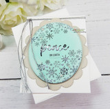 Snowflake heart on a teal oval, 'peace on earth,' with silver thread.