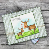 Scalloped card with two reindeer on green grass under a blue sky over carol-text paper, sentiment 'Happy Holidays, dearie'