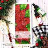Slimline card with the poinsettia in red and green beside buffalo-check ribbon and a gold pen.