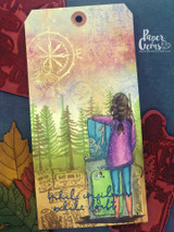 Mixed-media tag of the girl with her suitcase before a forest and compass.