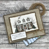 Handmade card featuring a cozy home framed by snowy evergreens, with the sentiment "Warm wishes for your home."