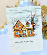 Handmade card featuring a cozy home framed by snowy evergreens, with the sentiment "Warm wishes for your home."