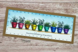 Kraft slimline card with the pots repeated and colored in rainbow jewel tones on a white ledge, over 'Happiness blooms from within.'