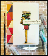 A girl holding a tall stack of books stamped in red rubber and colored on a handmade card reading "This is just one chapter, not the end of the story."