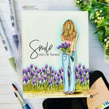 Card of the girl holding purple crocuses with 'Smile you're loved' in elegant script beside her.