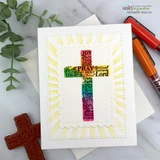 Card with the rainbow-colored word cross on a yellow sunburst background, red rubber cross block beside it.