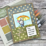 Polka-dot kraft card of the mouse with a yellow umbrella and the spring quote in a stitched frame.