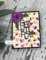 Sample card with a single plum bloom in the corner of a panel scattered with colored petal prints in yellow, pink and berry, on a black card base.