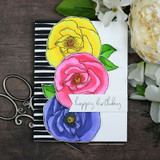Sample card with three blooms colored yellow, pink and periwinkle, die cut and stacked over a black and white striped panel, stamped 'happy birthday'.